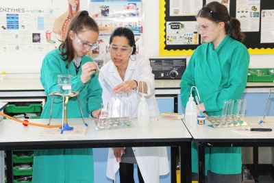 Lynne Chambers and two students in a lab wearing lab coats 